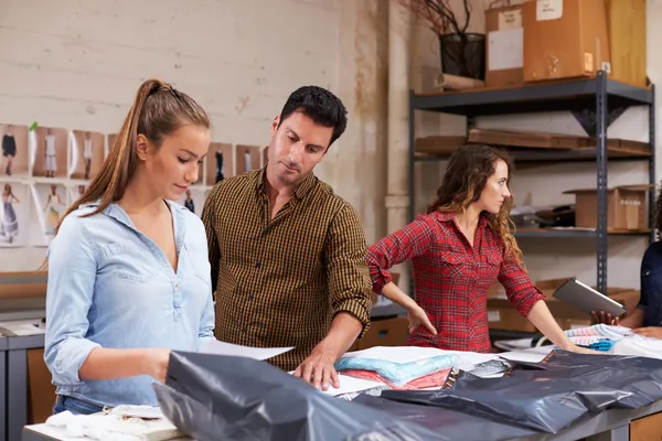 A warehouse manager audits the performance of an employee packing and shipping.