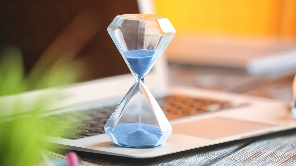 An hour glass sits on a laptop, representing a countdown to complete online purchases.