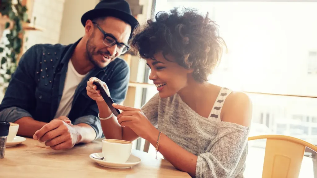 Women on smart phone shows her friend her favorite online brand while she recommends them.