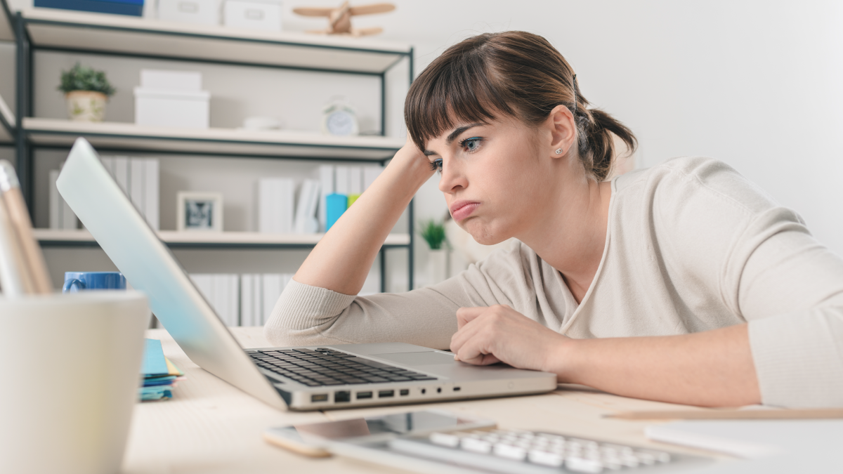 Frustrated woman stares at her computer, which is filled with spammy messages.