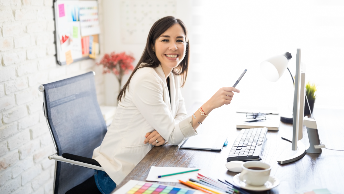 Smiling marketer woman stares at the camera while she sits at her desk.