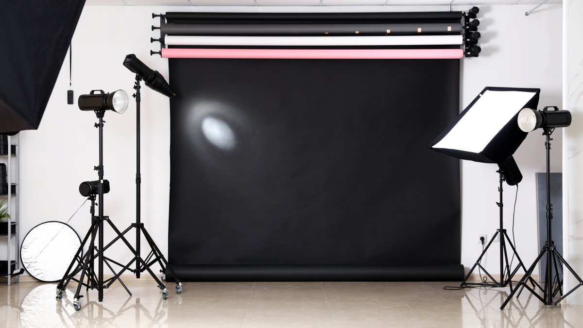 A photography space features several lighting fixtures and multiple vinyl backdrops.