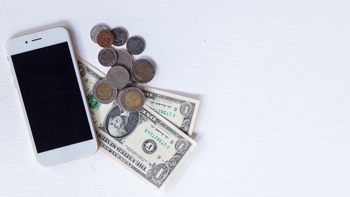 Smartphone laying on a pile of money.