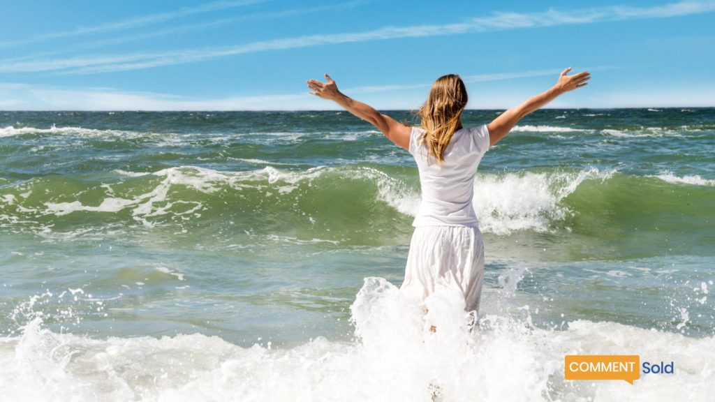 woman with arms out towards ocean and waves