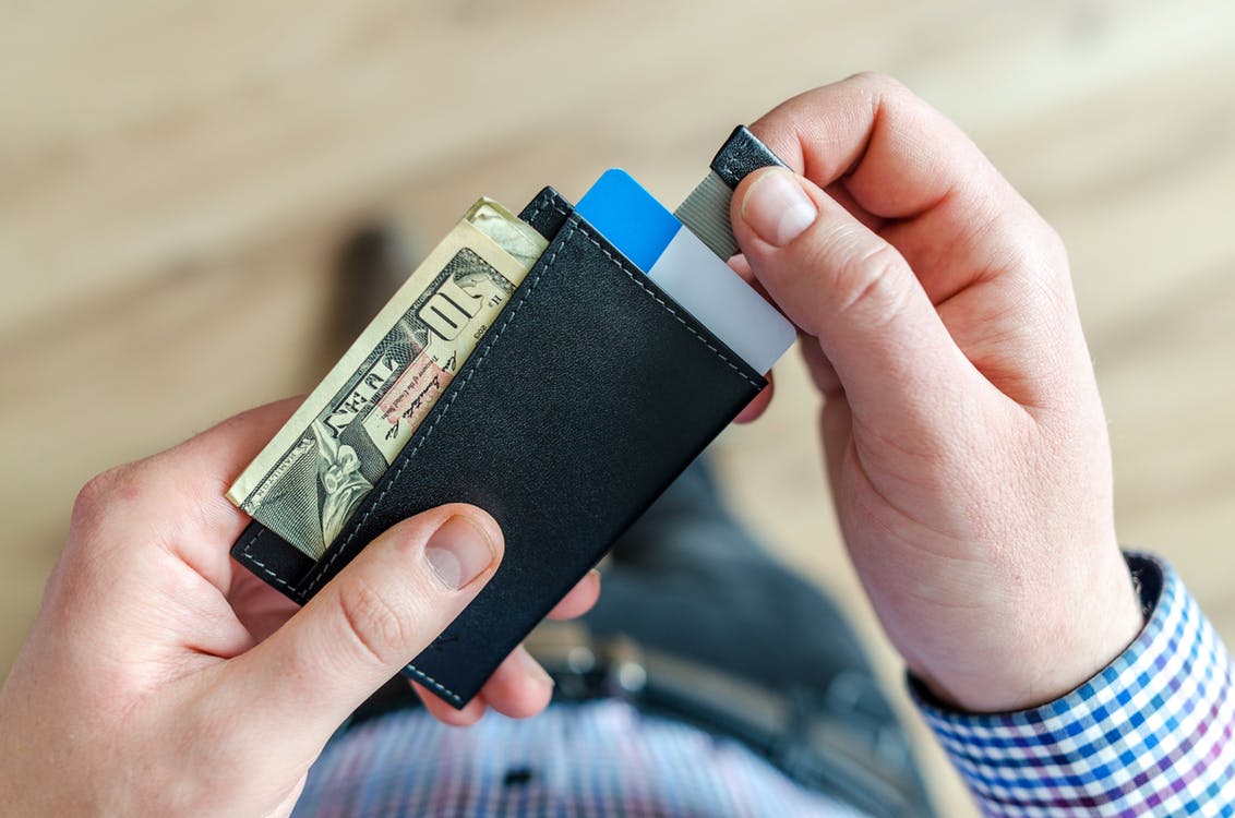 Person holding wallet prepares to spend more than the value of a giftcard
