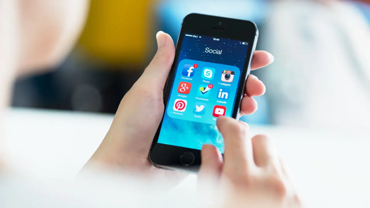 Woman holding her phone about to log into her social networks and promote her newly developed mobile app.